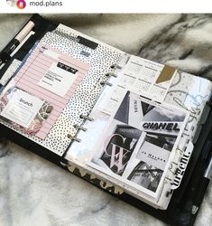 a black and white binder with many different things in it on top of a bed