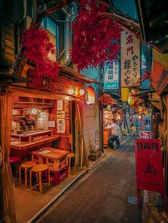 an alley way with tables, chairs and signs on the side walk at night time