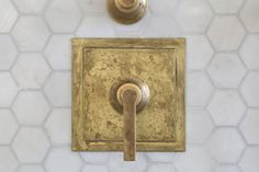 an old fashioned bathroom faucet is shown in gold and white marble with hexagonal tiles