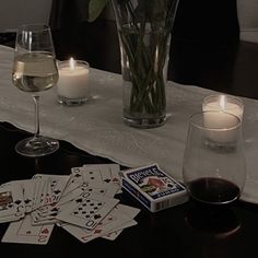 a table topped with cards and candles next to a vase filled with flowers on top of a table