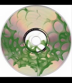 a cd that is sitting on top of a white surface with green and pink designs