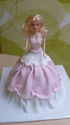 there is a barbie doll on top of a white cake with pink trimmings