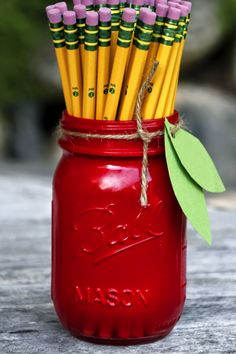 a red mason jar filled with yellow and purple pencils