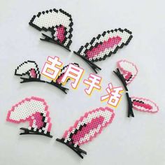 four pieces of pink and white beaded hair clips with black trims on them