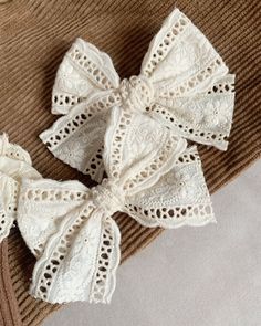 two white crochet bows on top of a sweater