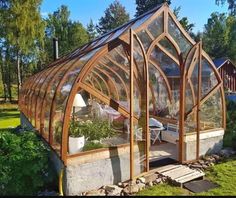 a small greenhouse in the middle of a yard with lots of plants growing inside it