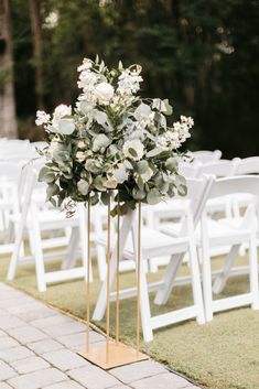 an outdoor ceremony with white chairs and flowers