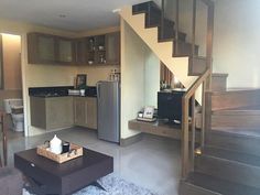 a living room filled with furniture and a metal refrigerator freezer sitting next to a wooden staircase