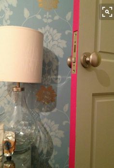 a lamp on a table in front of a blue and pink wallpapered room