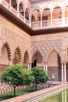 a woman standing in the middle of an ornate building with columns and arches on both sides