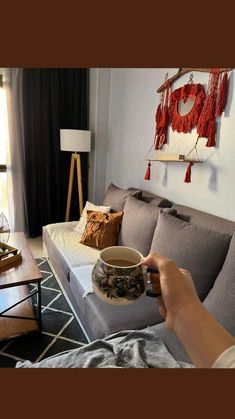 a person is holding a coffee mug in their hand while they sit on the couch