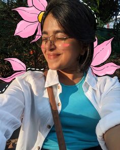 a woman sitting on a bench wearing glasses and a pink flower behind her head,