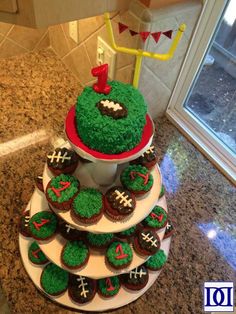 a three tiered cake decorated with cupcakes and green frosting on top