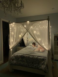 a woman laying in bed under a canopy with lights on the ceiling and curtains over her head