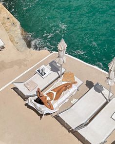 a woman laying on top of a white beach chair next to the ocean