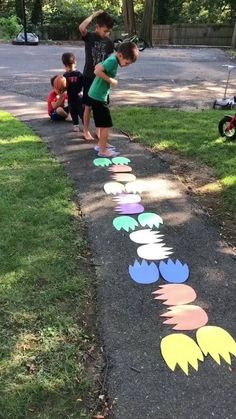 children are standing on the sidewalk painted with different colors and shapes to spell out words