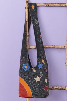 a handbag hanging on a ladder against a purple wall with stars and circles painted on it