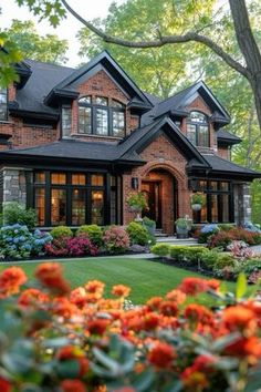 a large house with lots of flowers in front of it and trees around the yard