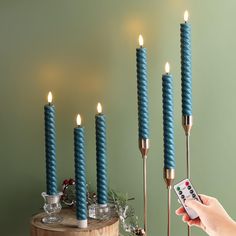 a person is holding a remote control in front of some candles with lights on them