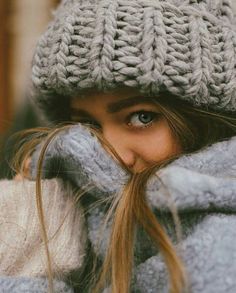 a close up of a person wearing a knitted hat and coat with long hair