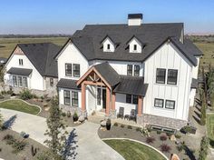 an aerial view of a large white house with black roofing and two car garages