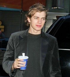 a young man is holding a drink and looking at the camera