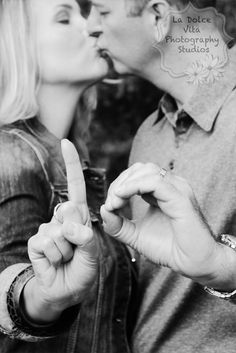 a man and woman kissing each other with the fingers in the shape of a peace sign