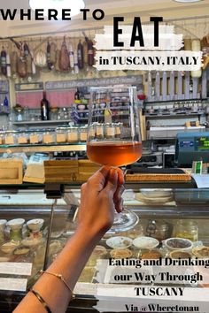 there is a person holding a wine glass in front of a display case with food on it