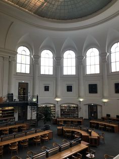 the interior of a large library with tables and bookshelves in front of two arched windows