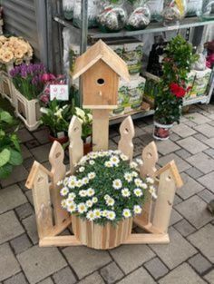 a wooden birdhouse with flowers in it on display at a flower shop for sale