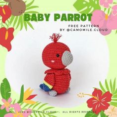 a crocheted baby parrot sitting in front of flowers