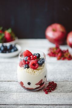 a dessert in a glass with berries and blueberries on top