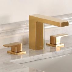 two golden faucets sitting on top of a marble counter