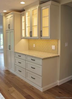 an empty kitchen with white cabinets and wood flooring in the middle of the room