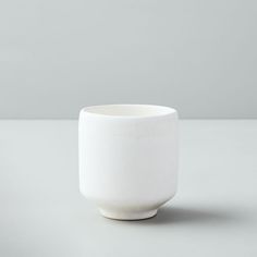 a white bowl sitting on top of a table next to a gray wall and floor