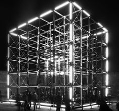 people standing in front of a large structure with lights on it