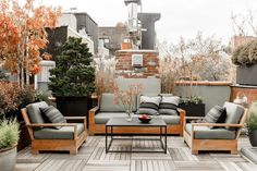 an outdoor living area with wooden furniture and potted plants on the roof top deck