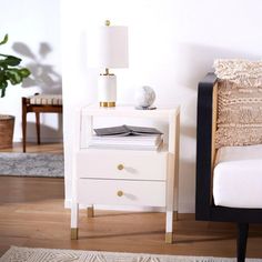 a white night stand with two drawers and a lamp next to it on a wooden floor