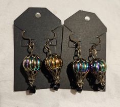 These hot air balloons earrings are made from metal and irredescent glass. The basket is a black square plastic bead. They are French hook dangle earrings. Hot Air Balloon Earrings, Balloon Earrings, Hot Air Balloons, Personalized Cups, Air Balloons, Christmas Earrings, Black Square, Plastic Beads, Hot Air Balloon