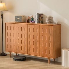 a wooden cabinet with holes on the front and sides, next to a floor lamp