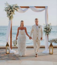 a bride and groom walking down the aisle at their wedding ceremony on the beach in front of the ocean