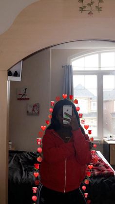 a woman taking a selfie in front of a mirror with hearts hanging from the ceiling