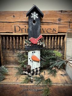 a birdhouse decorated with pine branches and an orange carrot sitting on top of it