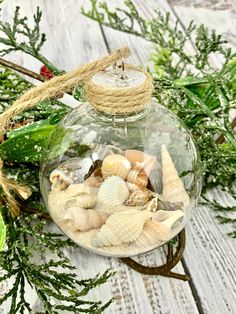 a glass ornament filled with sea shells on top of a white wooden table