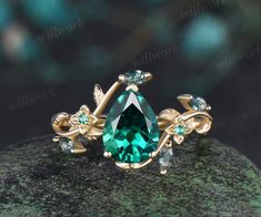 an emerald colored stone surrounded by green and white stones on top of a rock with gold accents