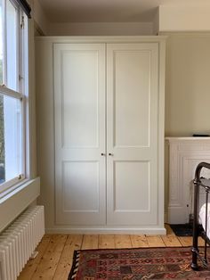 an empty room with a bed, armoire and rug on the floor next to a window