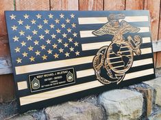 an american flag with the us marine service emblem on it is next to a stone wall