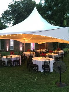 a large tent with tables and chairs set up for an outdoor function in the grass