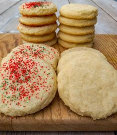 a wooden board topped with cookies covered in frosting and sprinkles