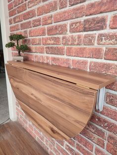 a wooden shelf on the side of a brick wall next to a potted plant